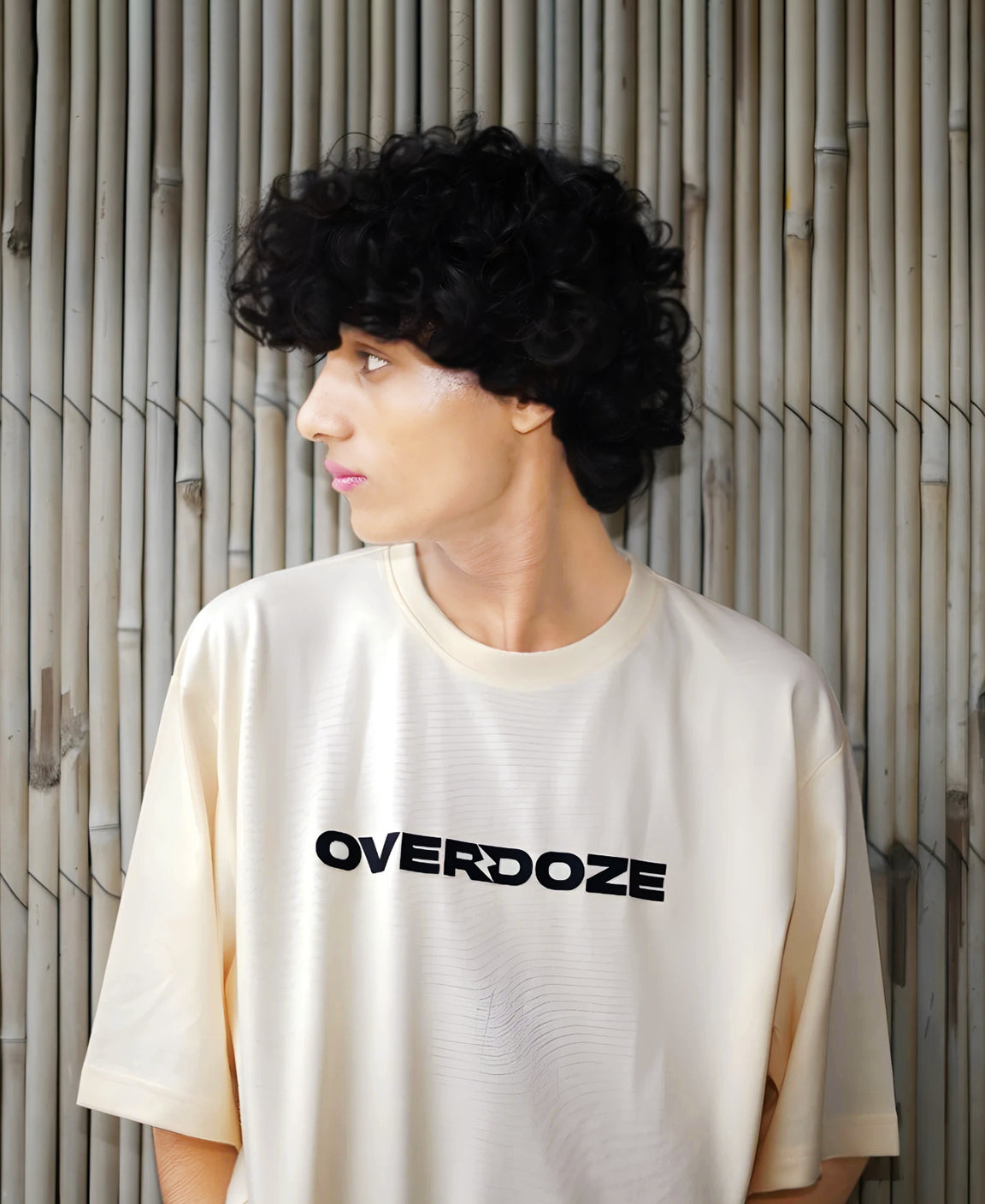 Person wearing a white t-shirt with 'OVERDOZE' logo against a bamboo wall.
